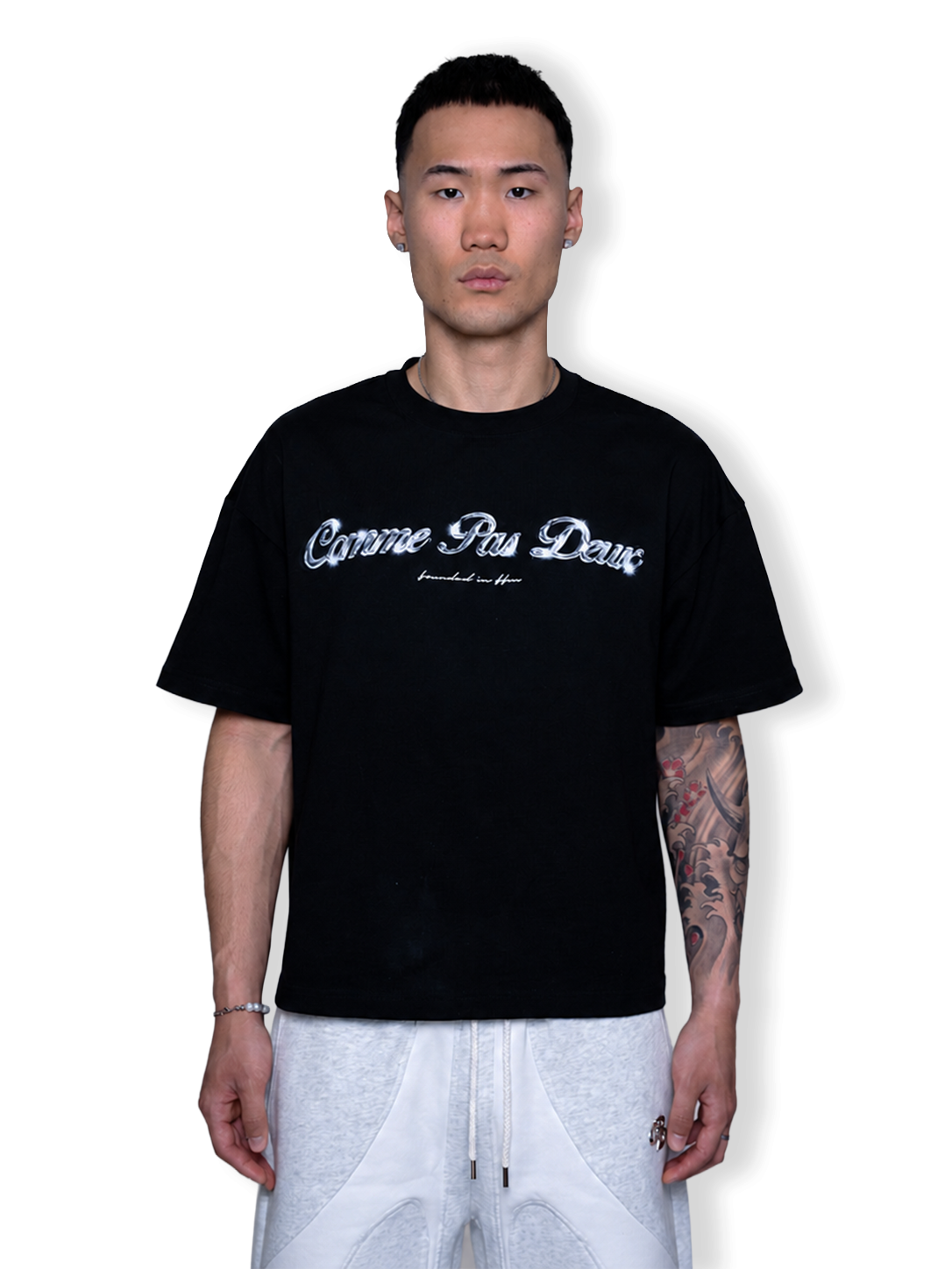Schwarzes, gekürztes Chrome T-Shirt von COMME PAS DE DEUX mit lockerer Passform, auf weißem Hintergrund liegend.